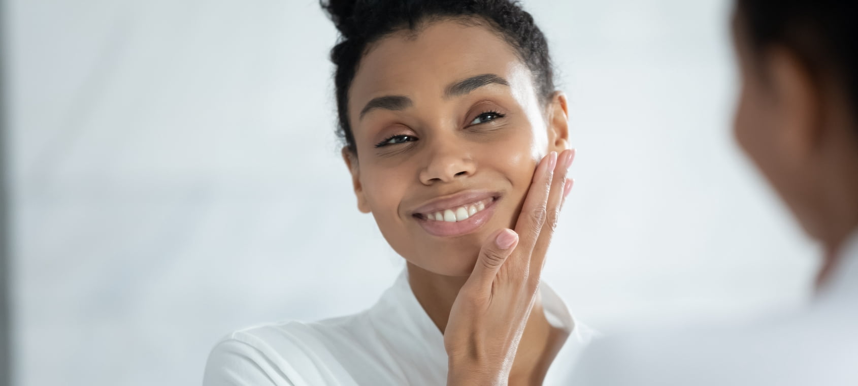 Black woman admiring her cleansed skin in the mirror